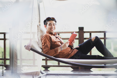 younger man relaxing by reading book on cradle