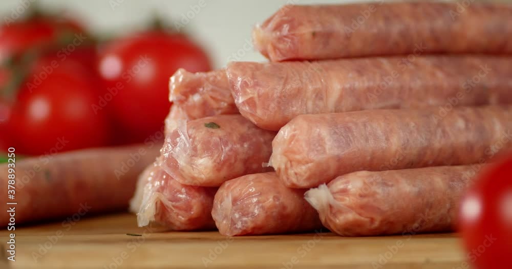 Fresh raw sausages with tomatoes slowly rotate. Fresh raw sausages with tomatoes slowly rotate.