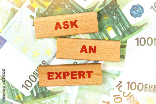 Against the background of euro bills, the text is written on wooden blocks - ASK AN EXPERT
