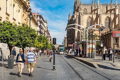 Seville, Spain. October 15th, 2020. Tram line stop at Avenida de la Constitucion with Cathedral in the background. Many people on the street. © Alessandro