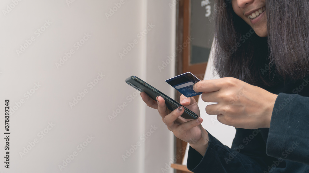 Smiling woman hands holding a blue credit card and using a smartphone for shopping online or internet banking with copy space. Online shopping concept. Smiling woman hands holding a blue credit card and using a smartphone for shopping online or internet banking with copy space. Online shopping concept.