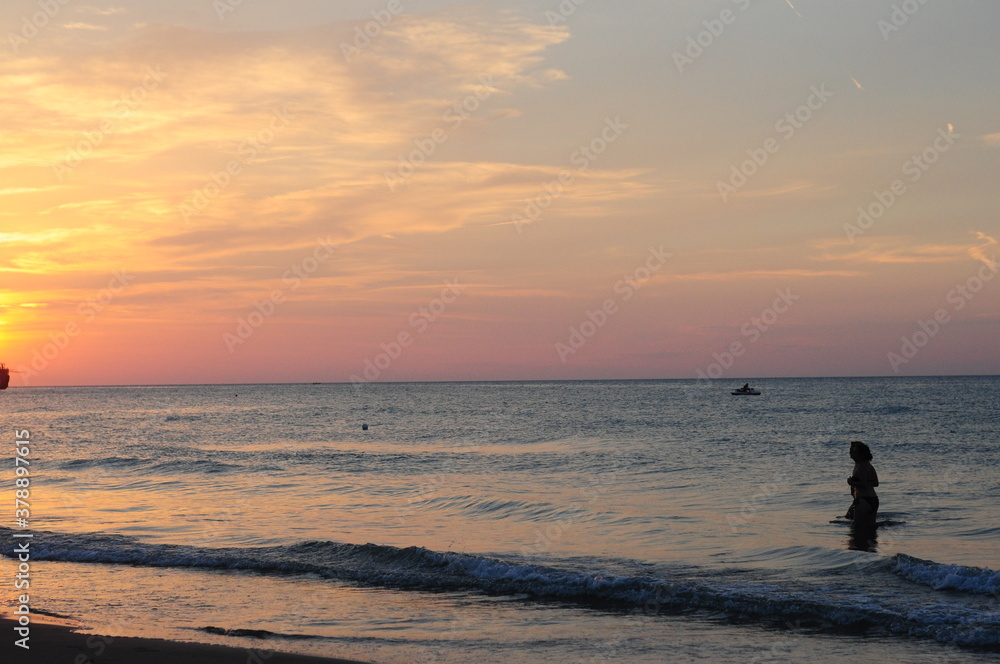 Peschici, Foggia - Sunset on a beach with peorle swimming in the sea