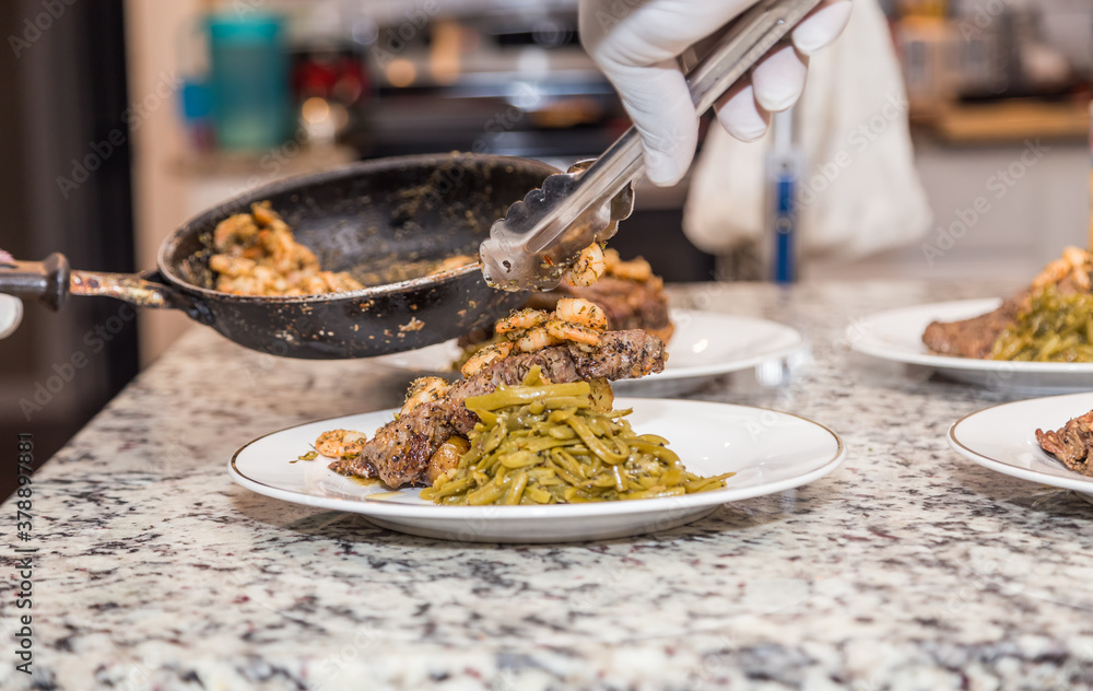 Φωτογραφία A chef ladles fresh au jus sauce over Rib eye Steak, green beans, and sautéed shrimp