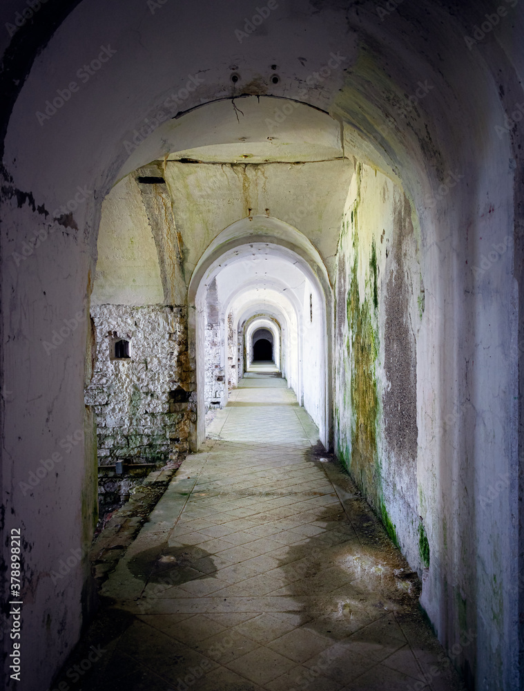 Corridor connecting the military fort in a state of neglect, walls dirty with mold and moss. Forte Leone, Cima Campo, Belluno, Italy