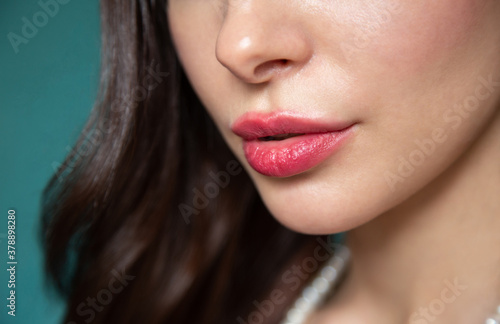 The lower part of the face of a beautiful girl close-up. Bright lips. Styled hair