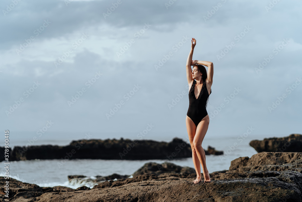 Portrait of pretty beautiful sport fashion woman in black bikini posing in summer near the ocean on tropic island on vacation Portrait of pretty beautiful sport fashion woman in black bikini posing in summer near the ocean on tropic island on vacation