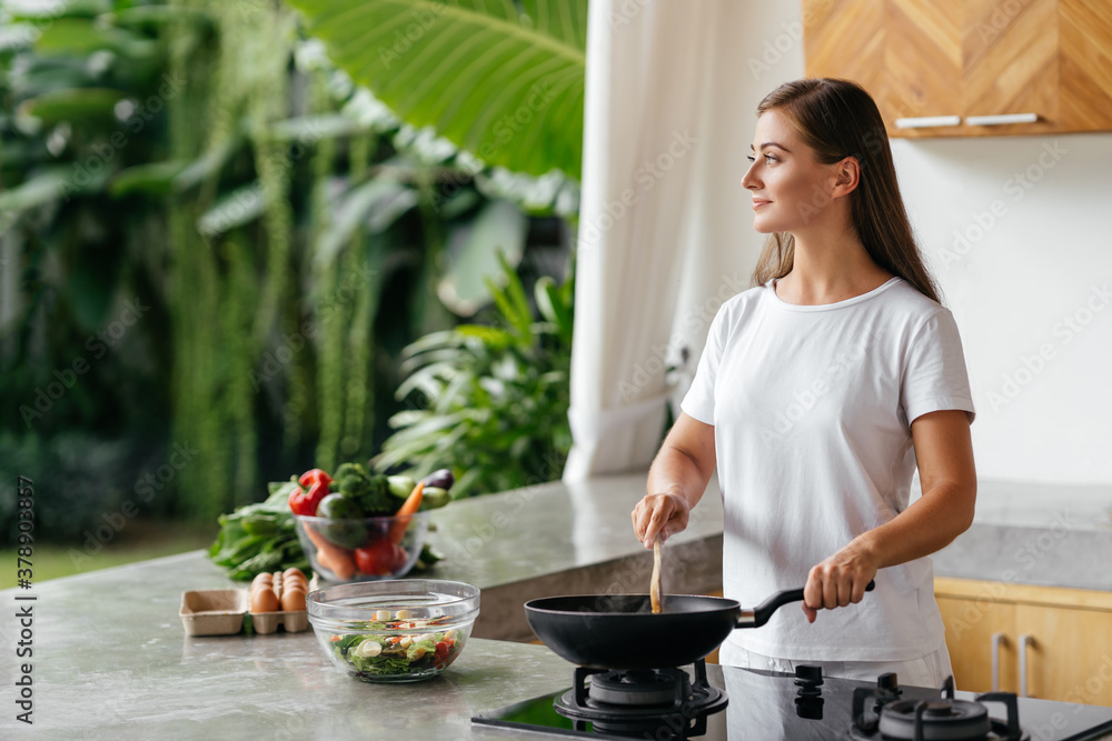 Young woman cooking in the open kitchen. Healthy Food. Dieting Concept. Healthy Lifestyle. Cooking At Home. Prepare Food Young woman cooking in the open kitchen. Healthy Food. Dieting Concept. Healthy Lifestyle. Cooking At Home. Prepare Food