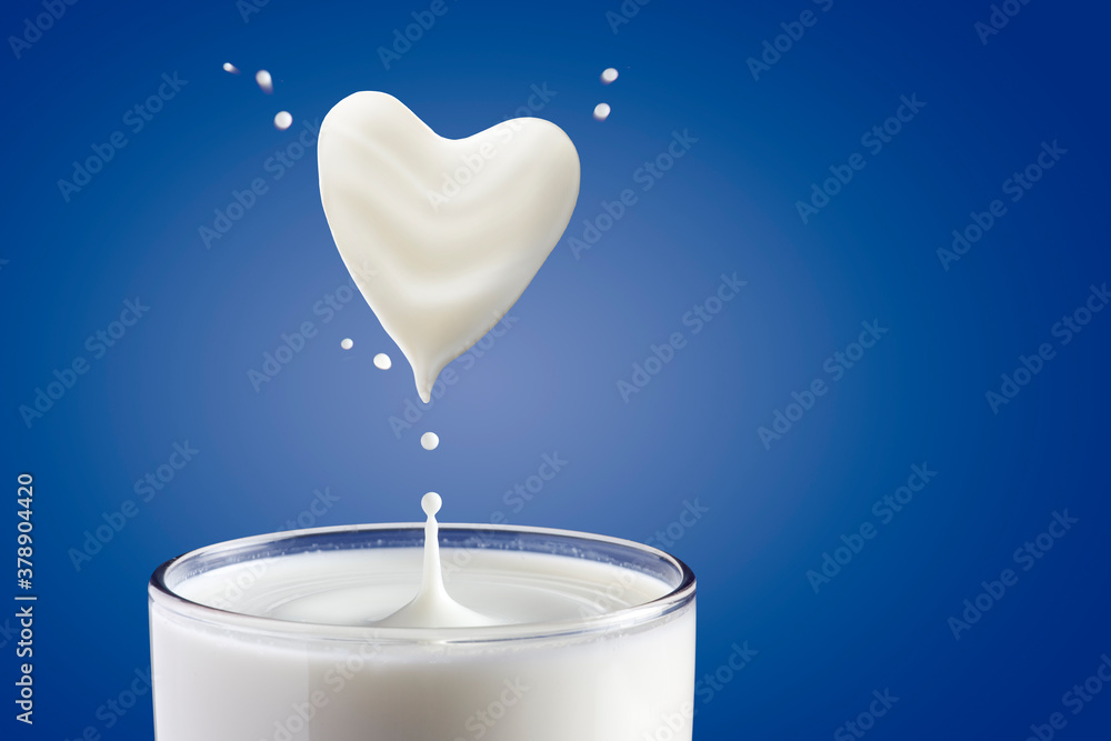 Milk pouring into glass and heart shape from milk - obrazy, fototapety, plakaty 