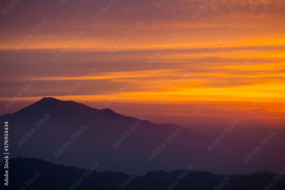 alone mount top silhouette on a dramatic sunset background