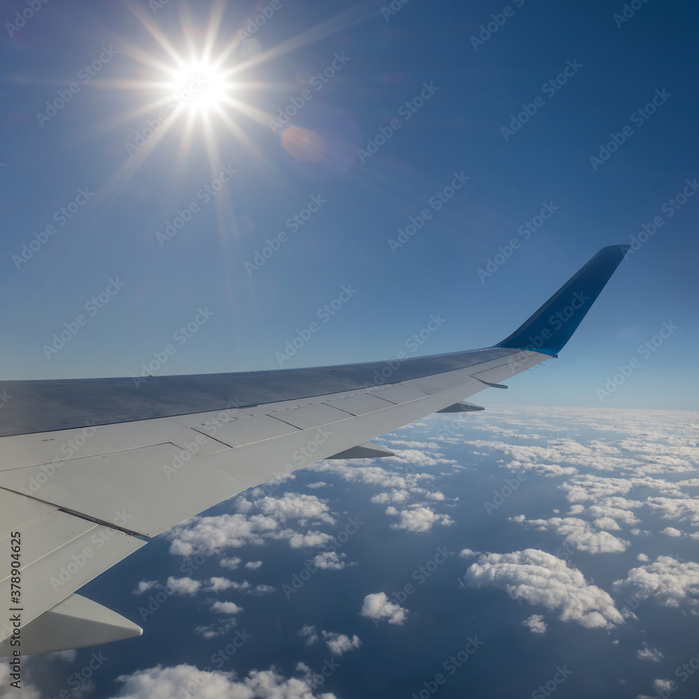 Fototapeta premium view from an airplane to a cloudy sky and sparkle sun, travel background