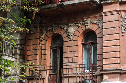 Mystical vintage cityscape. Old wooden windows of an obsolete vintage model on the wall of an old residential building. Wooden windows abandoned untrimmed residential old building