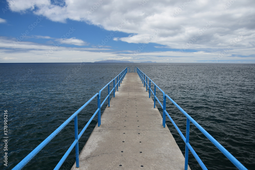 A little pier with a blue handrail at the coast of Santa Cruz, Madeira, Portugal.