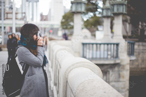 カメラを構えるグレーのコートの女性