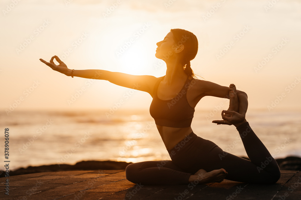 Yoga at sunset on the beach. woman performing asanas and enjoying life on the ocean. Bali Indonesia.