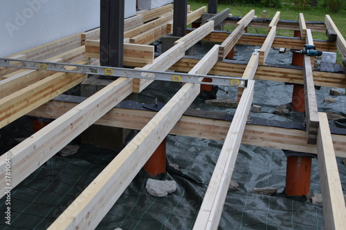 Backyard terrace construction - wooden frame for patio deck with foundation made of pipes filled with concrete. DIY concept.
