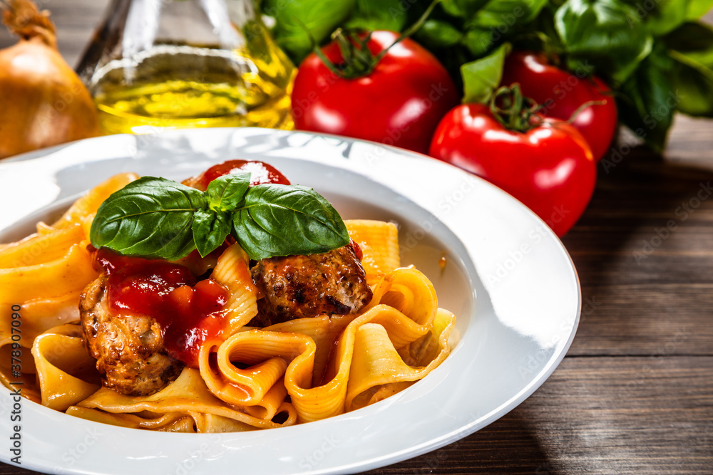 Pasta with meatballs in tomato sauce on wooden background
Pasta with meatballs in tomato sauce on wooden background