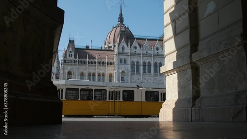yellow tram passing by the Hungarian Parliament building