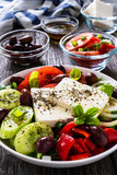 Fresh Greek salad - feta cheese, tomatoes, cucumber, red pepper, black olives and onion on wooden table
