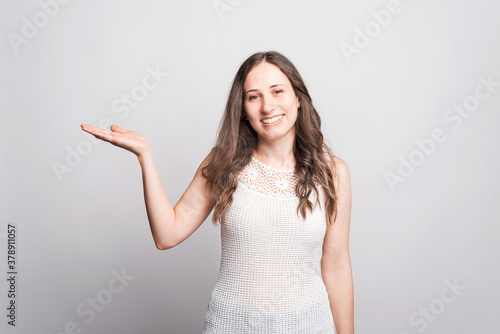 Portrait of young woman smiling and holding product on palm