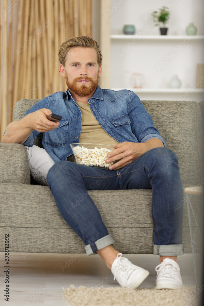 portrait an attractive man eating pop corn while watching tv