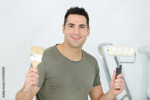 man holding roller brush and ordinary paint brush
