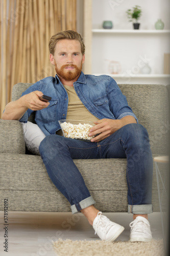 portrait an attractive man eating pop corn while watching tv