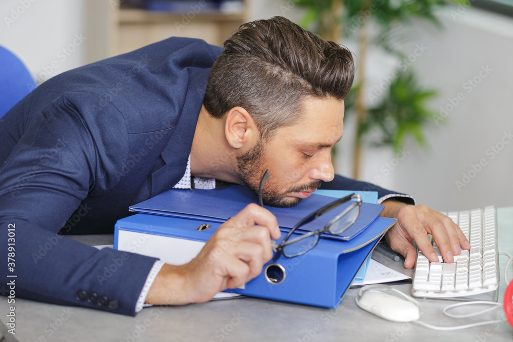 Naklejka premium man sleeping on top of a folder in the office