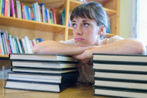overwhelmed woman leaning on a stack of books