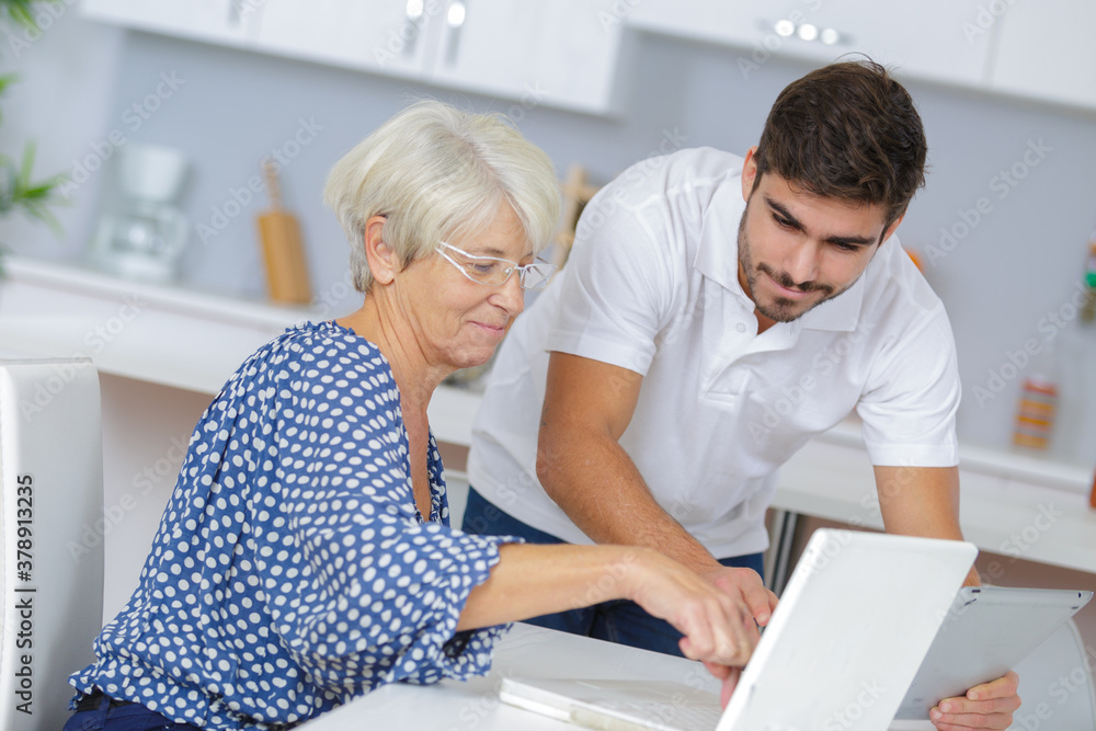 Obraz premium youngerman helping an elderly person using laptop computer