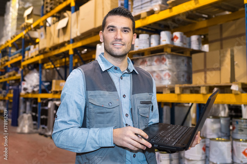 man using laptop in a warehouse