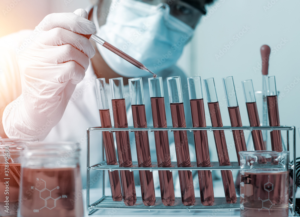 Scientist hand holding pipette dropping a sample into a test tube and ...