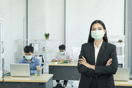 Portrait of young woman putting on a protective mask for example at the office to protecting themselves against corona virus. photo