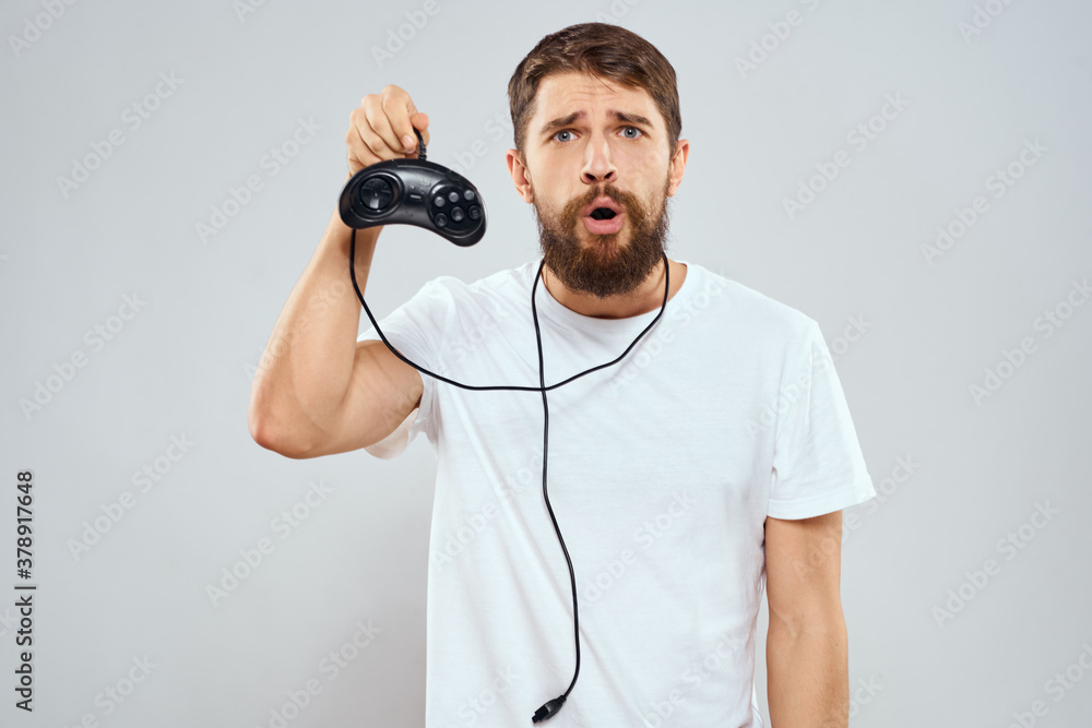 A man with a gamepad in his hands playing games leisure lifestyle technology white t-shirt light background A man with a gamepad in his hands playing games leisure lifestyle technology white t-shirt light background