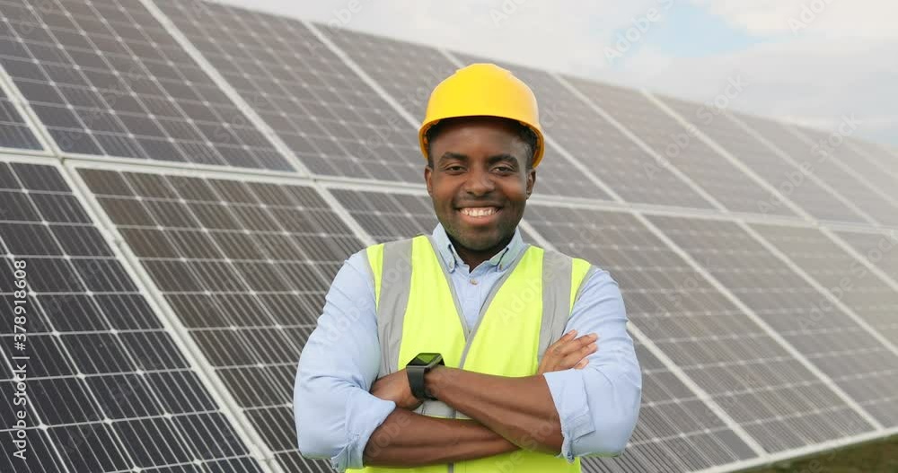 Close up portrait of young handsome African American craftsman a protective helmet. Happy man in overalls posing at camera smiling. Slow motion. Close up portrait of young handsome African American craftsman a protective helmet. Happy man in overalls posing at camera smiling. Slow motion.
