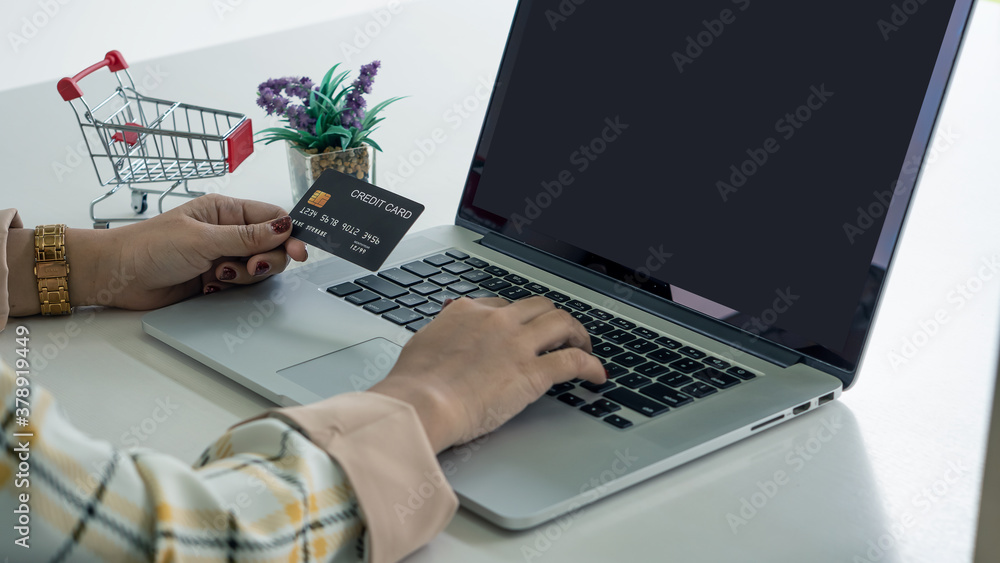 business owners who shop online use their credit debit card after work on the laptop computer sitting inside the office. Women shopping online business owners who shop online use their credit debit card after work on the laptop computer sitting inside the office. Women shopping online