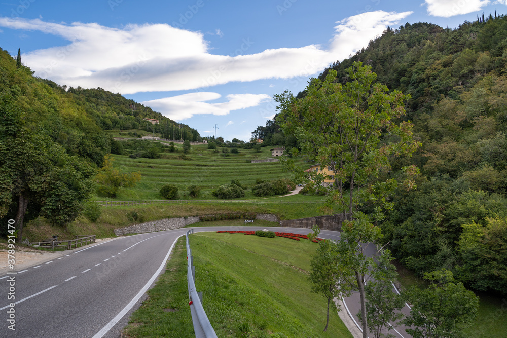 Curvy road in the mountains of italy with blue cloudy sky