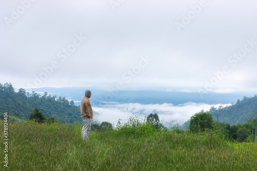 Young man looking beautiful view of foggy mountains landscape