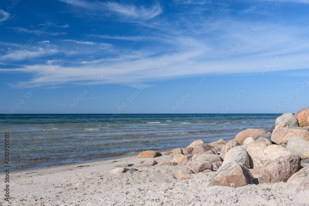 Runde Stein als Verbauung am Sandstrand vor Meer, Himmel mit Leichter Bewölkung Runde Stein als Verbauung am Sandstrand vor Meer, Himmel mit Leichter Bewölkung