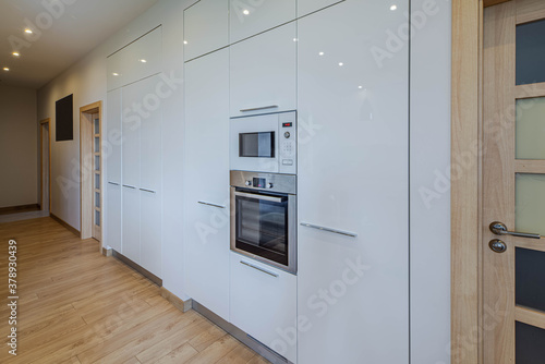 Wall with built-in kitchen set with oven and microwave. Contemporary interior. Luxury flat.