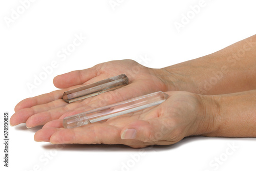 Crystal Therapy Energy in Energy Out concept - Female open palms with left clear quartz terminated crystal pointing inwards and right hand smoky quartz wand pointing outwards isolated on white  