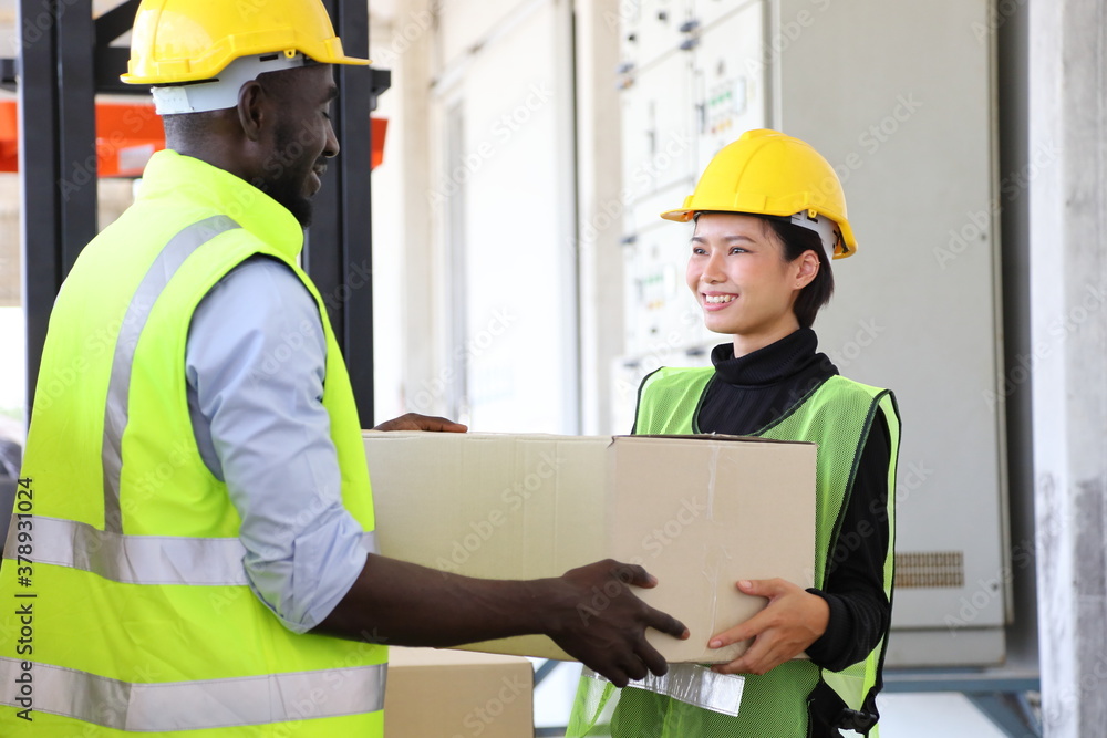 African American and Asian warehouse worker helping each other as teamwork to carry the product package to be ready for shipping African American and Asian warehouse worker helping each other as teamwork to carry the product package to be ready for shipping