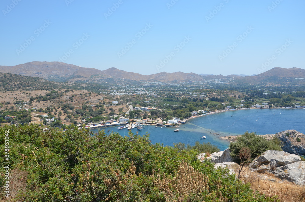 Top view of an entire bay of the Aegean Sea. Sailboats and boats moored. Settlements spread over the hills.