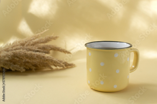 A cup of black tea in a ceramic yellow cup with field herbs on a yellow background. Selective focus. Horizontal orientation. photo