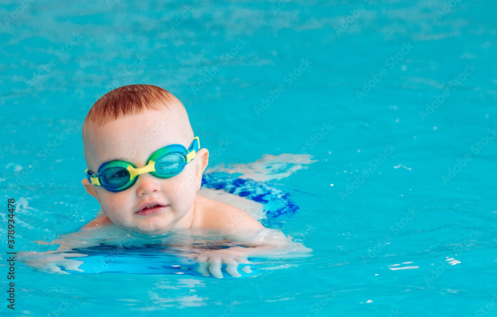 Naklejka premium Baby boy swims independently in the pool.