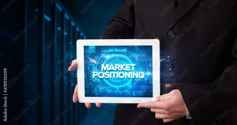 Young business person working on tablet and shows the inscription: MARKET POSITIONING, business concept Young business person working on tablet and shows the inscription: MARKET POSITIONING, business concept