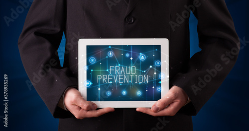 Young business person working on tablet and shows the digital sign: FRAUD PREVENTION