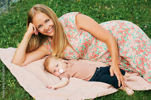 Happy young mother relaxing with baby in park or garden