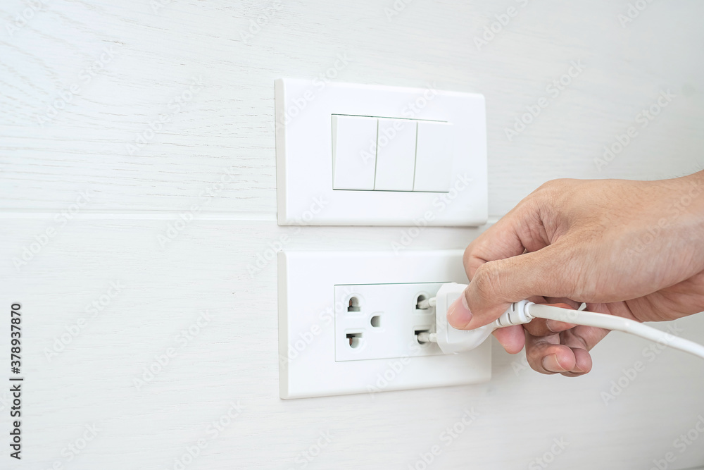 Closeup Male finger unplugging or plugging of electricity device on white wall at home. Energy Saving, power, electrical and lifestyle concepts Closeup Male finger unplugging or plugging of electricity device on white wall at home. Energy Saving, power, electrical and lifestyle concepts