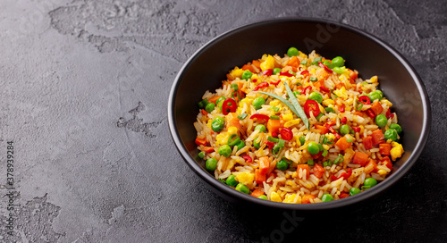 Asian fried rice with egg and vegetables. Stone background. Close up. Copy space.