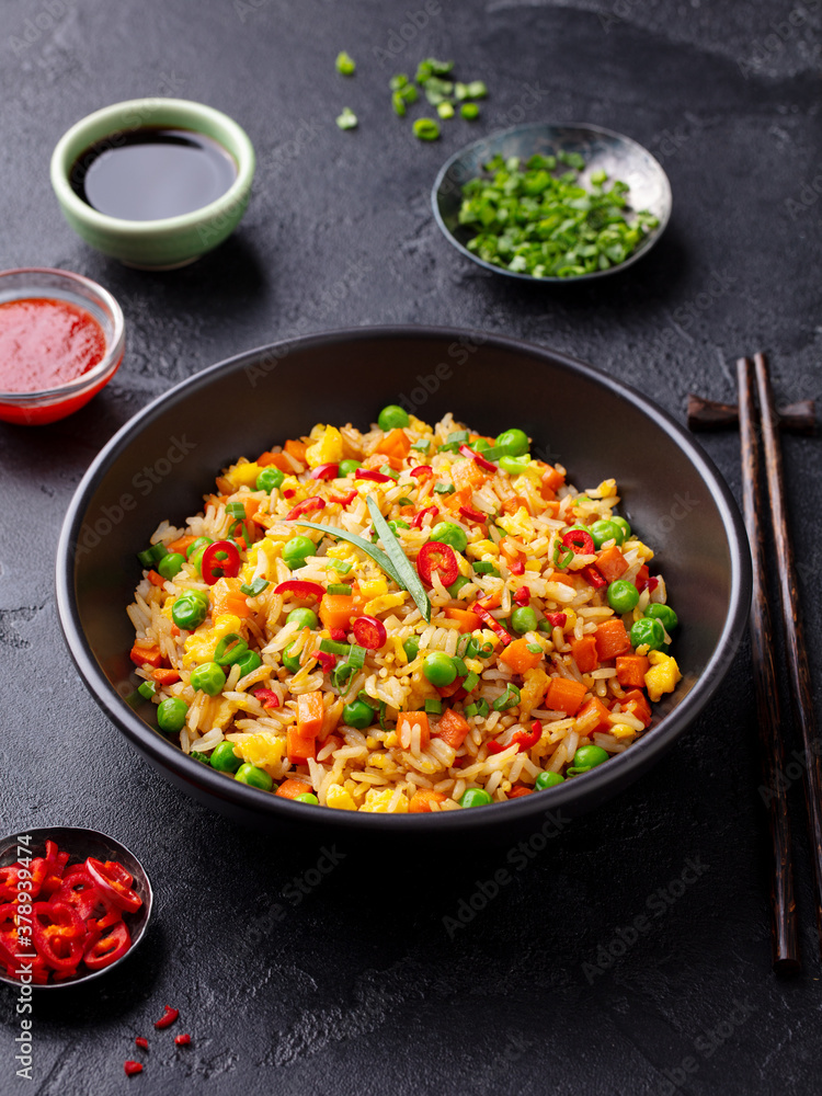 Asian fried rice with egg and vegetables. Dark stone background. Asian fried rice with egg and vegetables. Dark stone background.